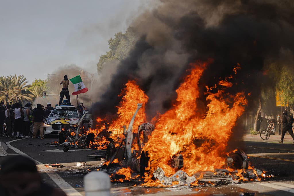 Protesters Photographed Holding Mexican Flag in Front of Burning Vehicle