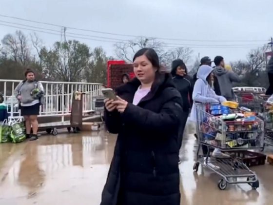 A woman uses her cell phone to record a mob of scavengers that descended on a dumpster outside a supermarket in Austin, Texas, on Thursday after the store discarded food potentially spoiled by a power outage.