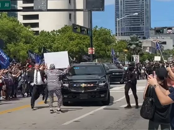 Anti-Trump demonstrator Dominic Santana walks in front of Trump's motorcade in Miami, Florida, on Tuesday.
