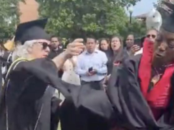 A recent college graduate rips the microphone away from a faculty member. (@rahsh33m / Twitter)