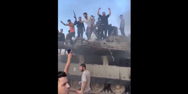 Hamas fighters are seen with a disabled Israeli tank its captured crew on the morning of Oct. 7, 2023.