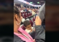a mother looking on as a man sitting next to her son at a hockey game intercepts a puck that might have hit him