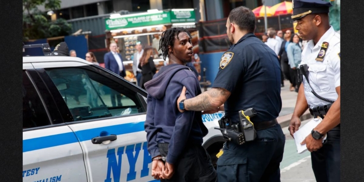 Police detain one of three suspects in Thursday's machete stabbing of a street vendor.