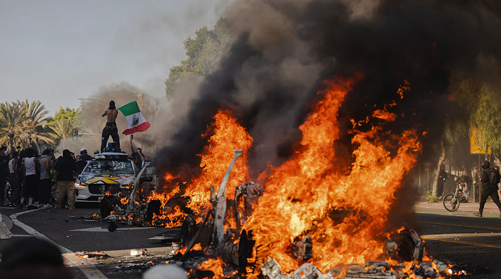 Protesters Photographed Holding Mexican Flag in Front of Burning Vehicle