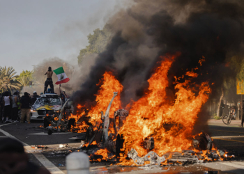 Protesters Photographed Holding Mexican Flag in Front of Burning Vehicle